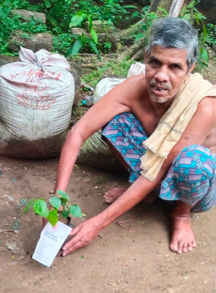 Community participant beside a tagged planted sapling